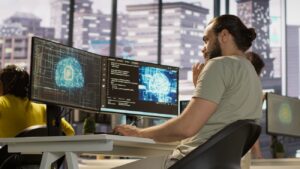 Employee utilizing AI resources and platforms to train and deploy machine learning models, handheld camera shot. Man monitoring and maintaining artificial intelligence company systems, camera A